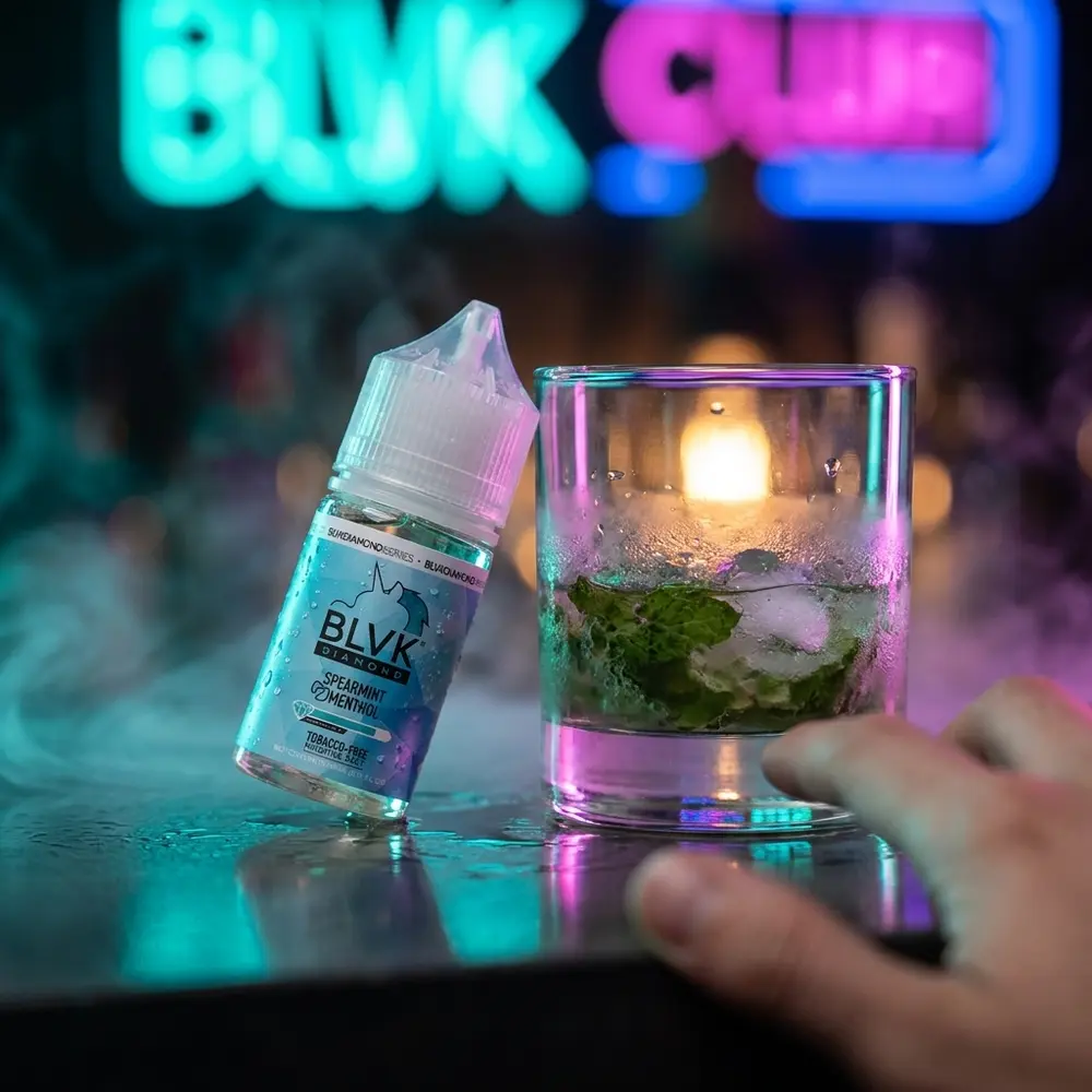 Frasco Blvk Unicorn Salt no balcão noturno com luzes neon desfocadas, copo e folhas de hortelã ao lado - Vapor Gringo
