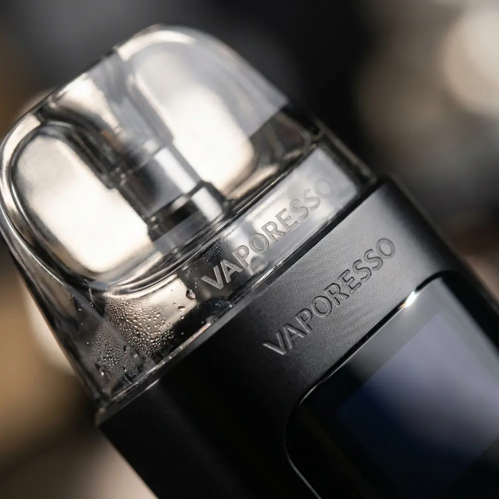 Close-up do Kit Pod Luxe XR Max mostrando logo, acabamento metálico, pod transparente e gotas de condensacao - Vapor Gringo